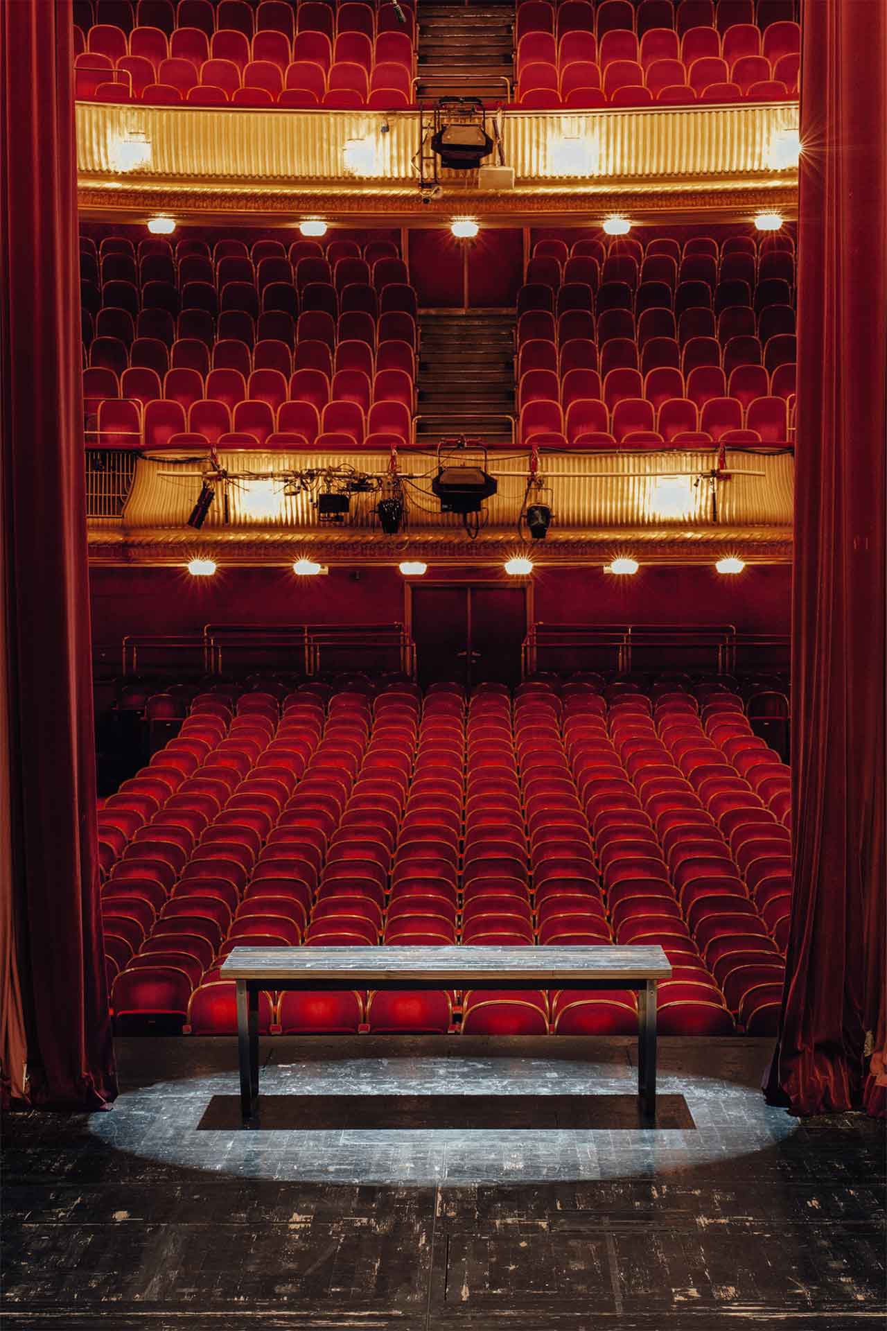 Blick von der Bühne in einen historischen Theatersaal mit roten Sitzreihen